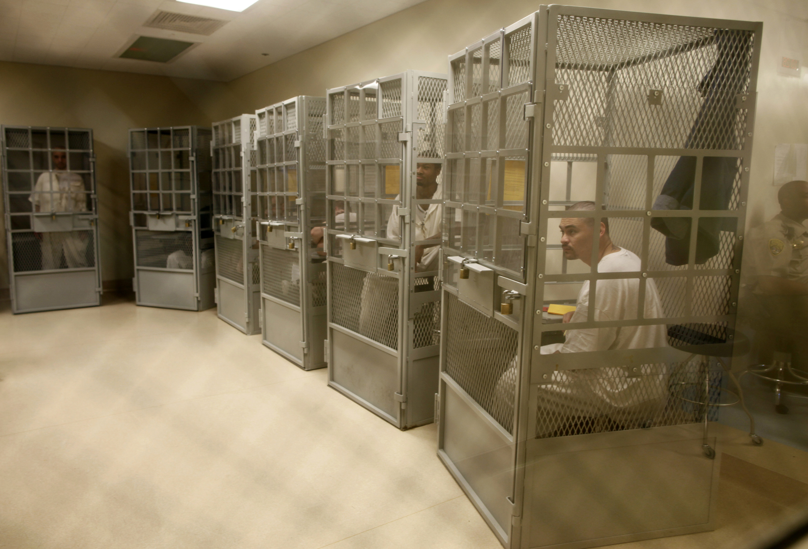 Inmates sit inside small caged enclosures for counseling in San Quentin.